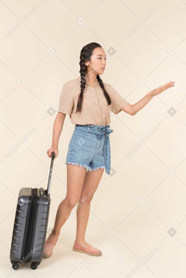 Mulher asiática com uma bagagem chamando um táxi