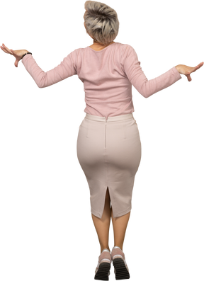 Вид сзади женщины в повседневной одежде, стоящей на цыпочках и вытягивающих руки