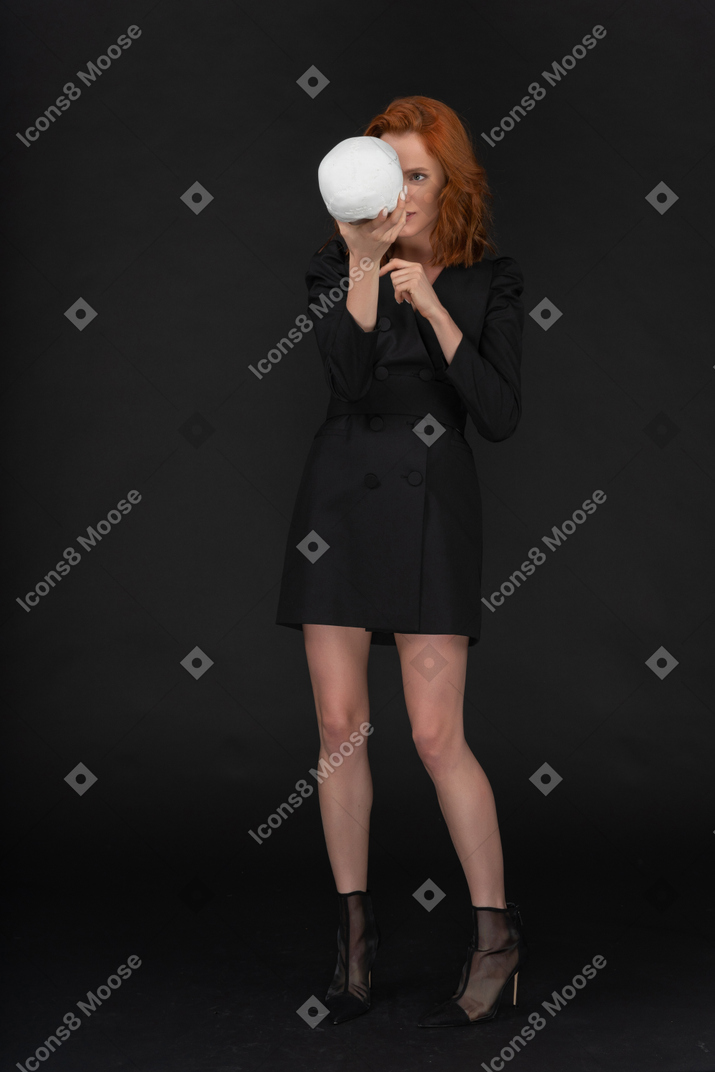 A frontal view of the beautiful young girl holding a skull and talking to it