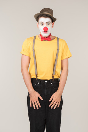Surprised male clown standing with hands on elongated