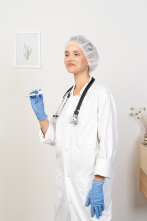 Three-quarter view of a young female doctor with stethoscope holding thermometer