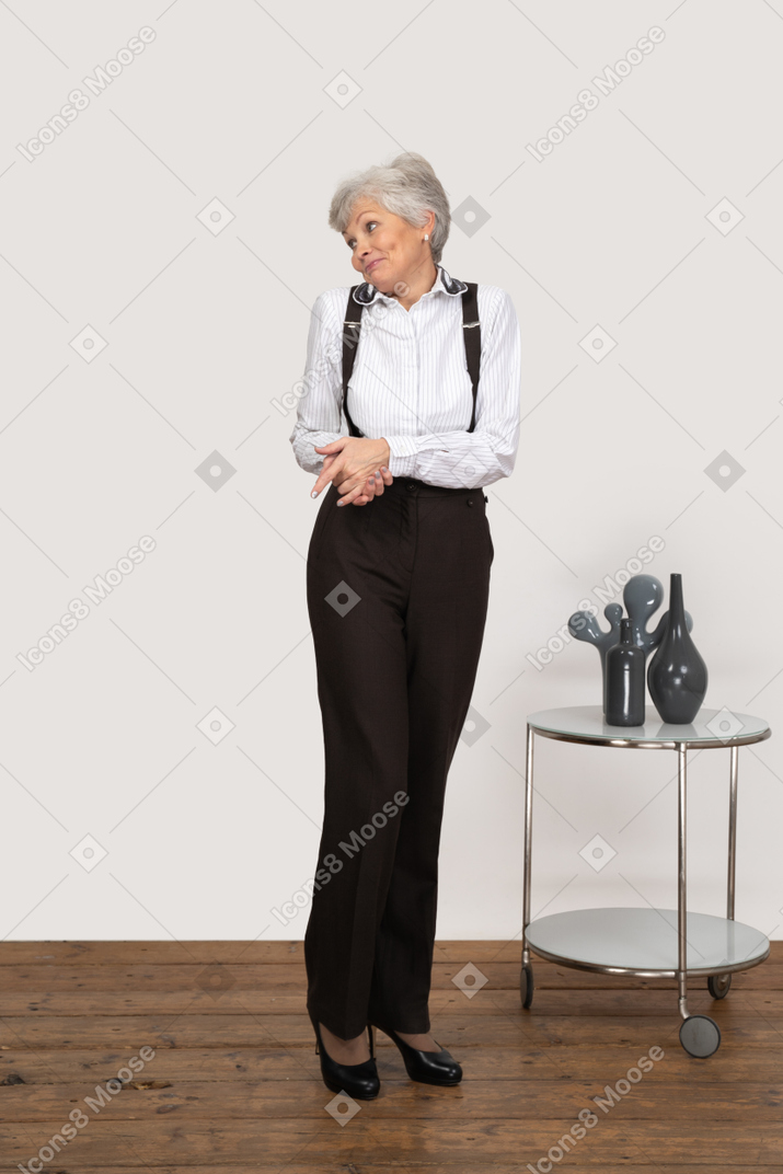Front view of a shy old lady in office clothing holding hands together