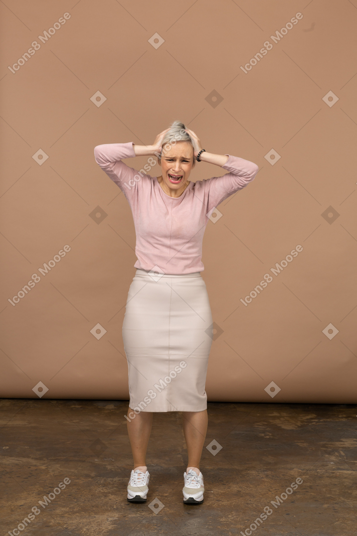 一个穿着休闲服、双手放在头上的情绪化女人的正面图
