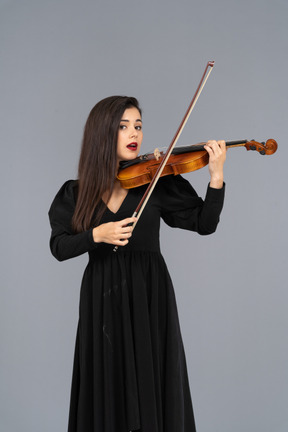 Close-up de uma jovem de vestido preto tocando violino