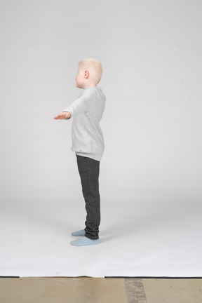 Vista lateral de un niño estirando las manos hacia un lado