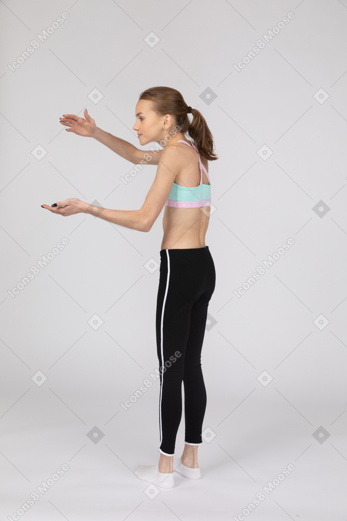 Vista laterale di una ragazza adolescente sorpresa in abiti sportivi alzando le mani