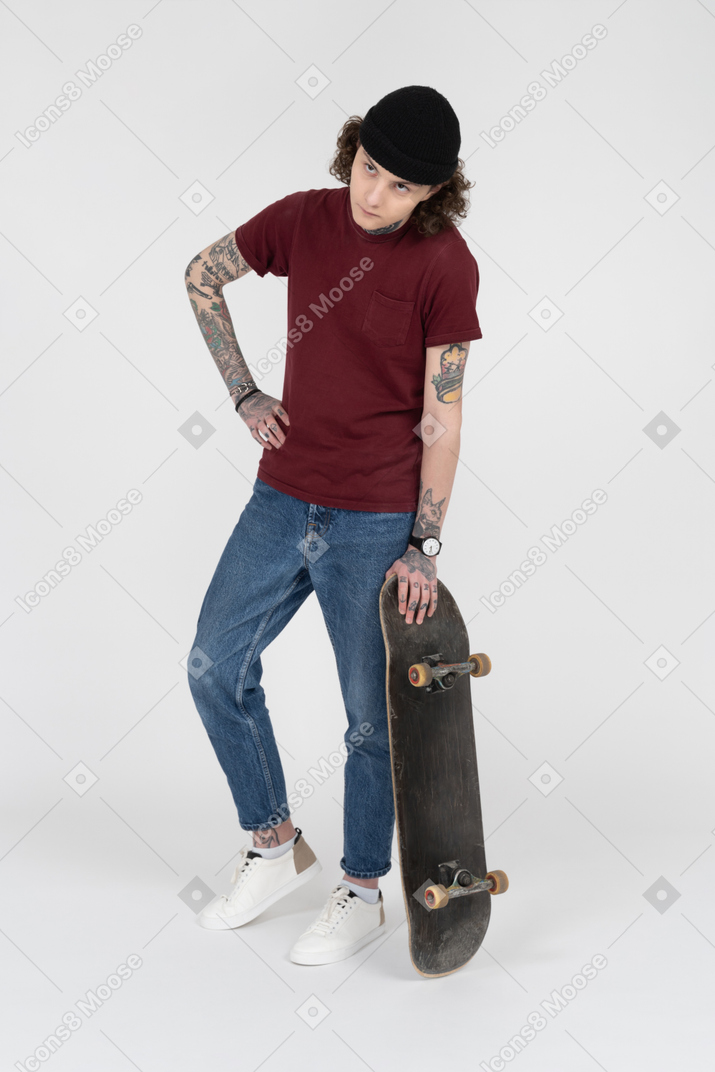 Um adolescente de pé com seu skate