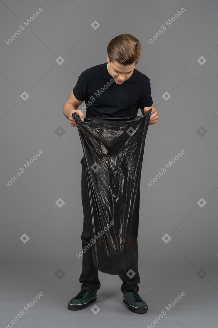 A young man looking inside a trash bag