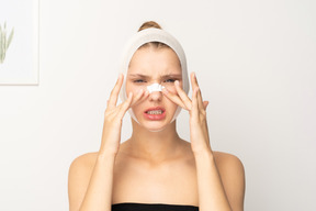 Mujer joven con vendaje en la cabeza colocando curita en la nariz