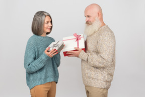 Elegante pareja de ancianos dando regalos el uno al otro