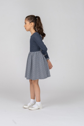 Side view of a girl with hands behind her back looking uncertain