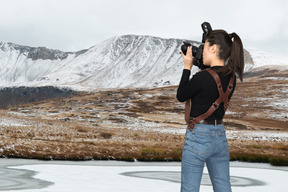 A woman taking a picture of a snowy mountain
