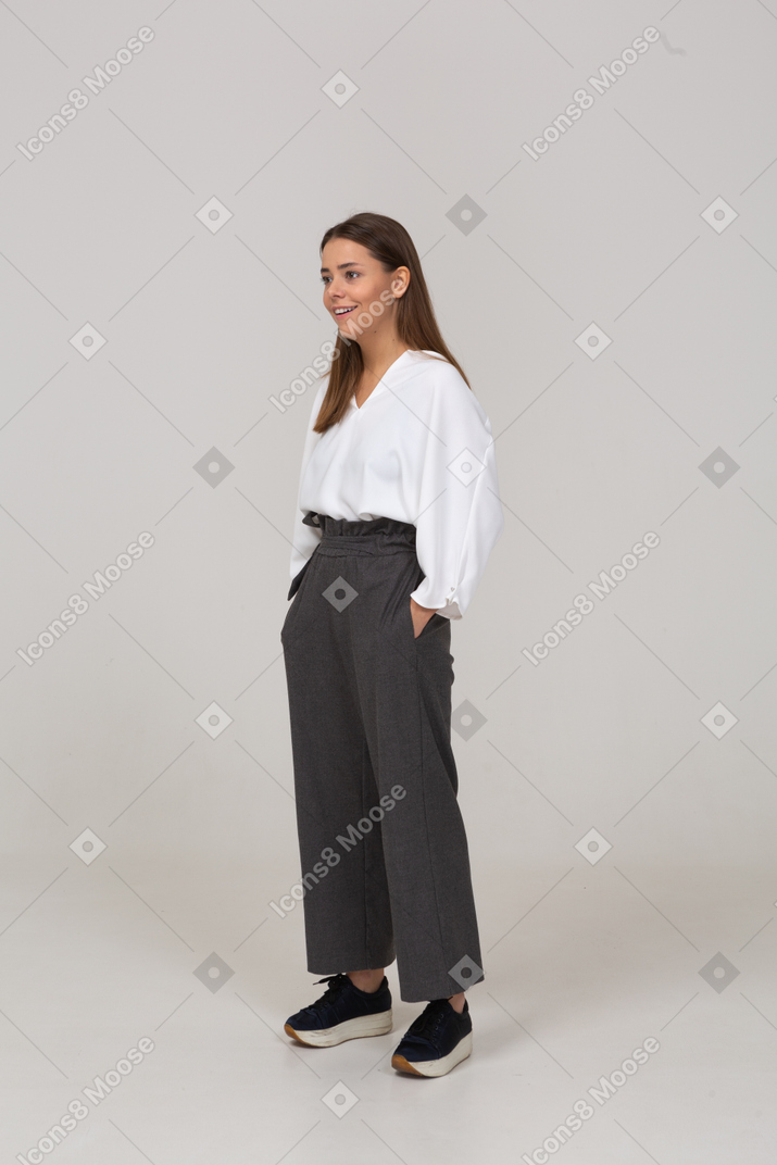 Three-quarter view of a young lady in office clothing putting hands in pockets