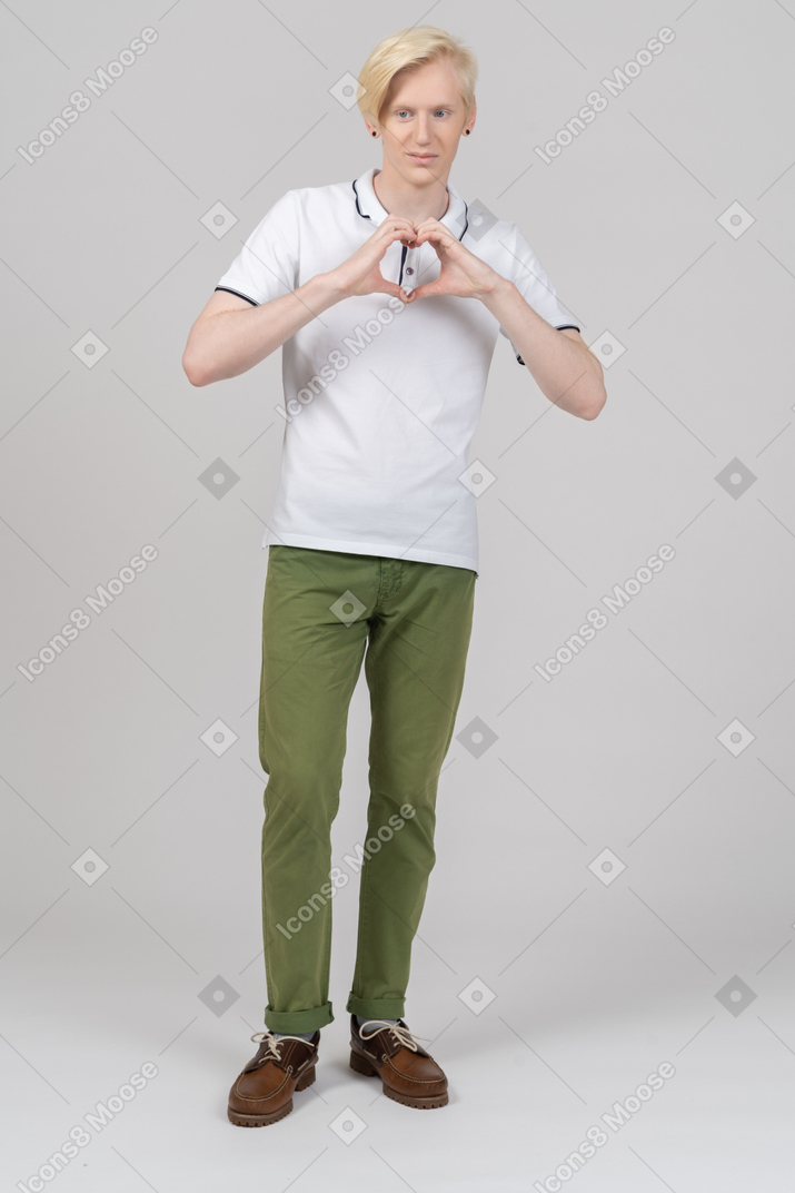 Vista frontal de um jovem mostrando um sinal de coração com os dedos