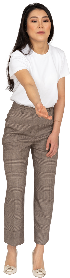 Vista frontale di una giovane donna in calzoni e t-shirt protendendo la mano