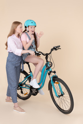 자전거를 타는 방법을 흥분 십 대 소녀를 가르치는 젊은 여자