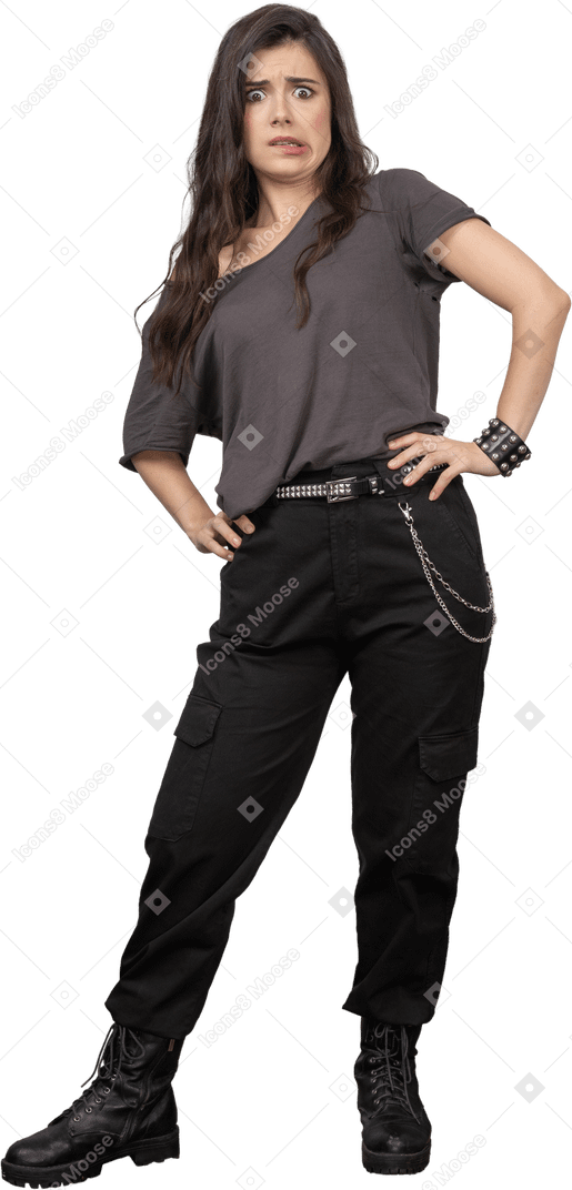 Front view of a surprised grimacing female rocker putting hands on hips
