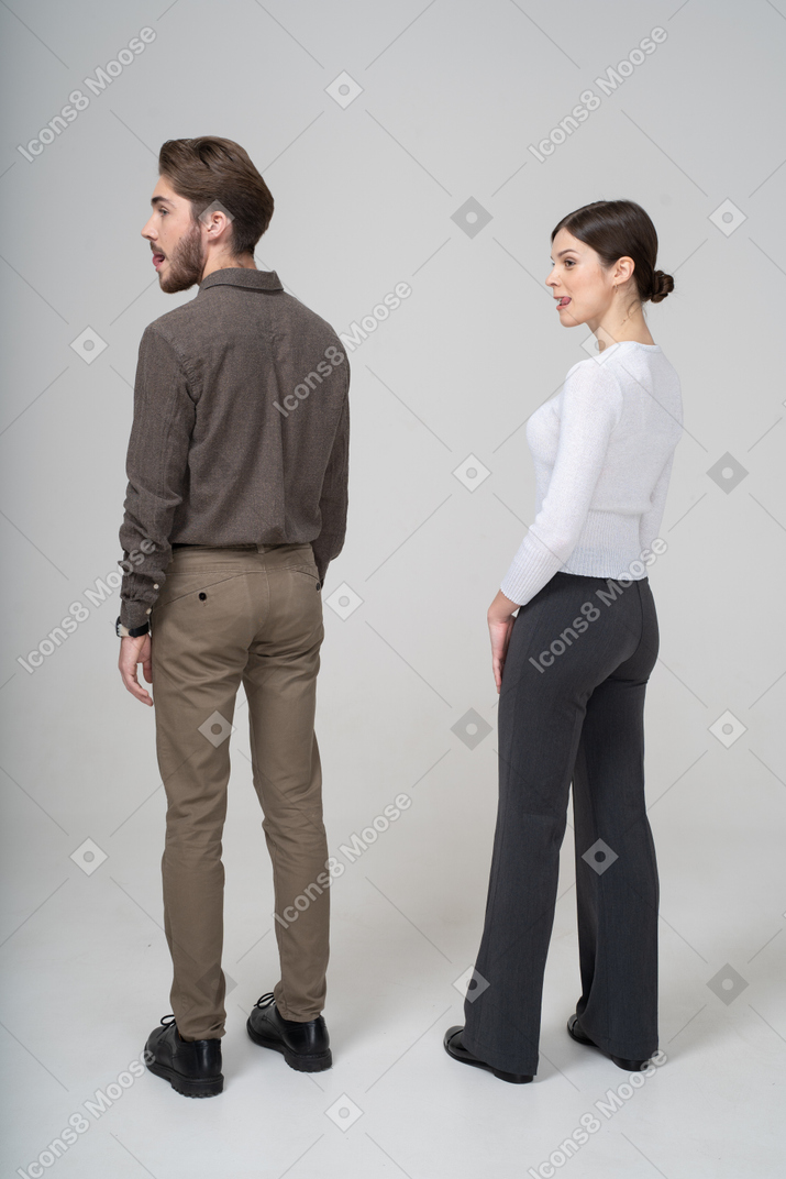 Трехчетвертный вид молодой пары в офисной одежде, показывающей язык