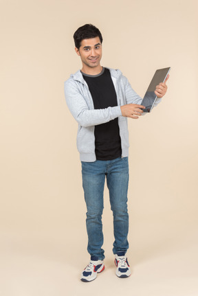 Young caucasian man pointing at a digital tablet he's holding