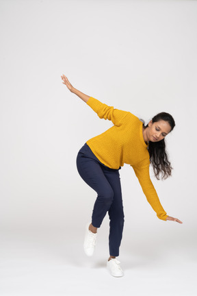 Front view of a girl in casual clothes posing on one leg with outstretched arms