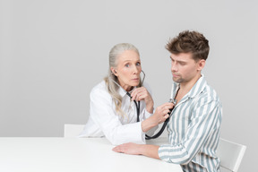 Doctora de edad examinando a un paciente con un estetoscopio