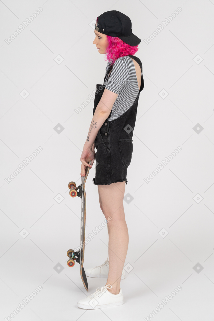 Hunchbacked teenage girl holding a skateboard in profile