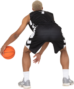 Vista posteriore di un giovane giocatore di basket maschile che fa dribbling