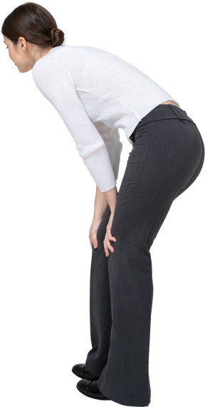 Side view of a young woman in casual clothes bending down