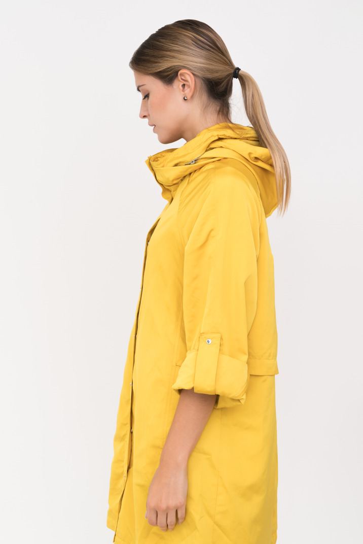 Girl in yellow coat standing in profile