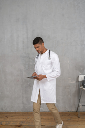 Male doctor looking at tablet while walking