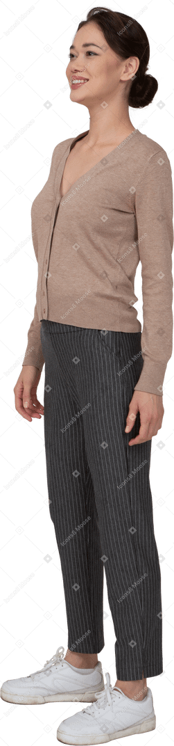 Vue de trois quarts d'une femme souriante en pull et pantalon