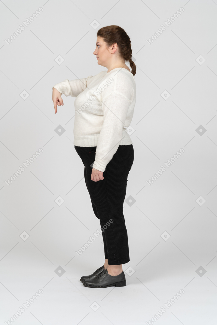 Femme dodue dans des vêtements décontractés pointant vers le bas
