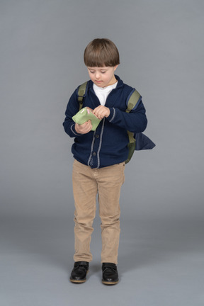 Kleiner junge mit einem rucksack, der ein federmäppchen hält
