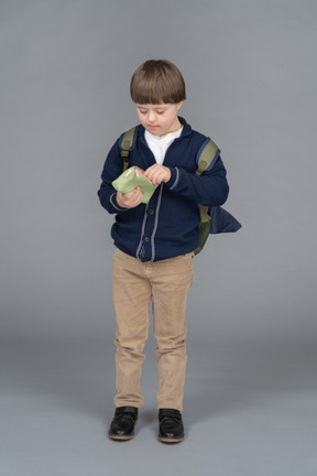 Little boy with a backpack holding a pencil case