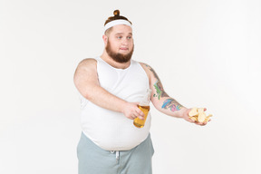 Un hombre gordo en ropa deportiva compartiendo cerveza y papas fritas