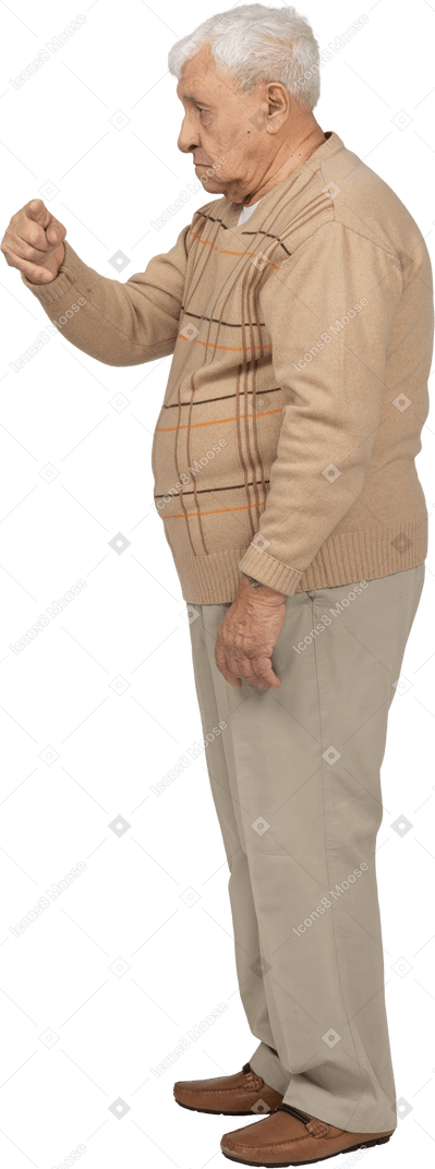 Side view of an old man in casual clothes pointing with finger