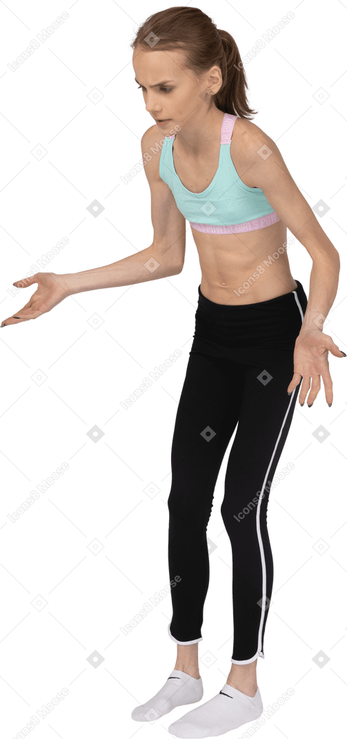 Three-quarter view of a teen girl in sportswear pointing hands somewhere down