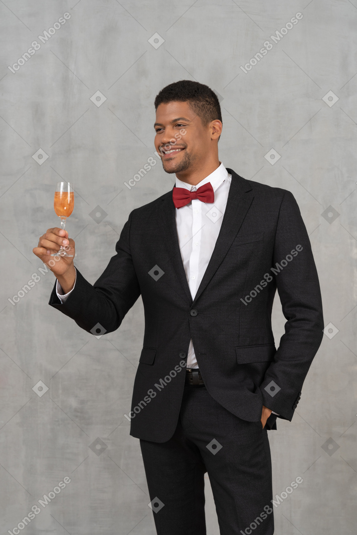 Lächelnder mann, der ein glas champagner anhebt