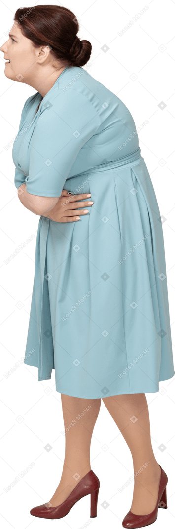 Вид сбоку на женщину в синем платье, страдающую от боли в животе