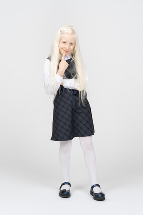 Schoolgirl smiling mischievously with finger pressed to mouth