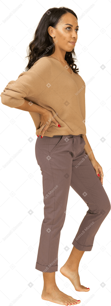 Vue de trois quarts d'une femme à la peau sombre dans des vêtements décontractés mettant la main sur la hanche