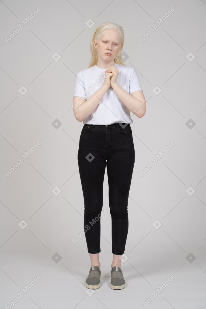 Young woman in casual clothes standing with folded hands