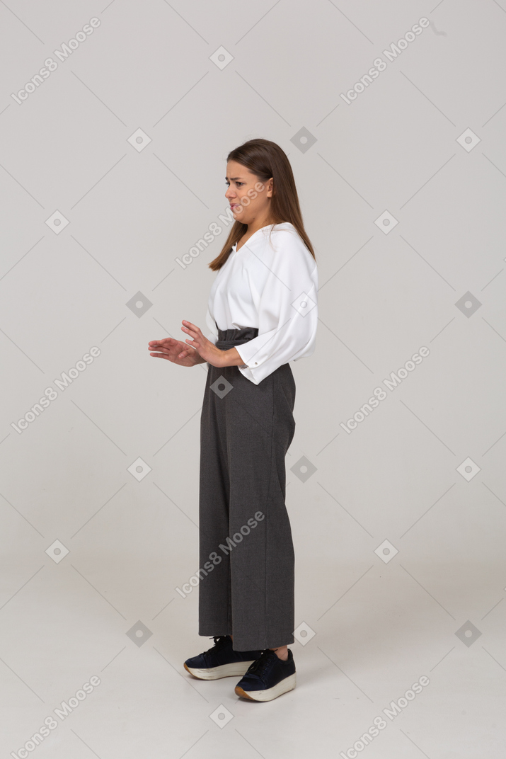 Three-quarter view of an unwilling young lady in office clothing outstretching arms