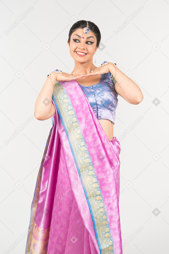 Junge inderin in lila sari stehend mit gefalteten händen