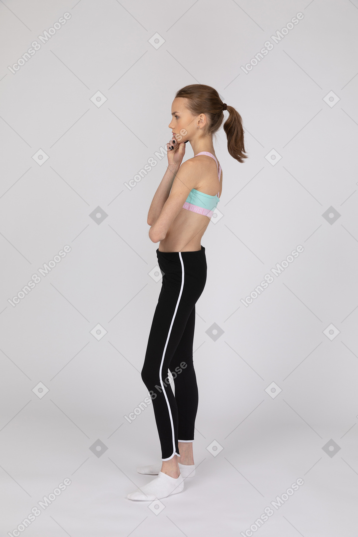 Vista lateral de uma adolescente em roupas esportivas levantando a mão e discutindo