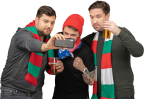 Front view of three male football fans taking selfie