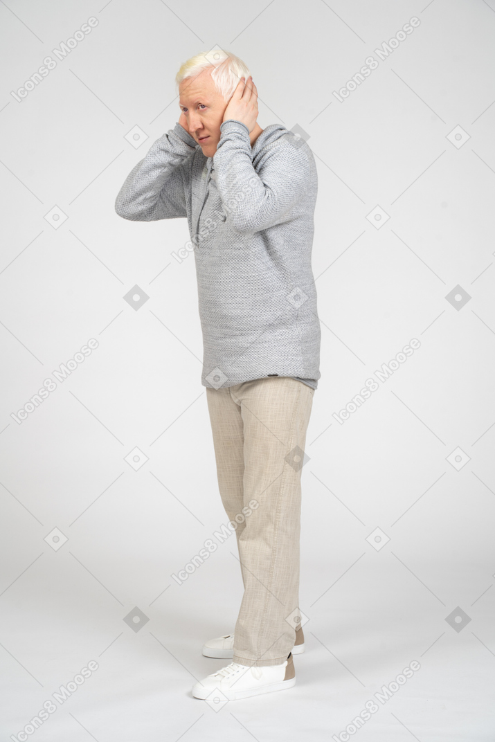 Man in hoodie and trousers covering his ears