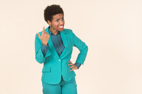 Black woman with a short haircut, wearing all blue, standing against a plain pastel background, looking emotional