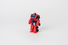 A toy transformer figure of red and black colours standing against a plain white background