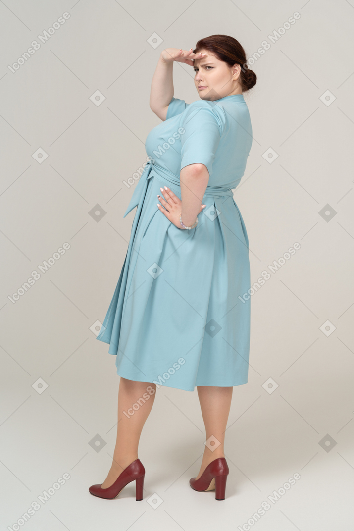 Vista posteriore di una donna in abito blu che cerca qualcuno